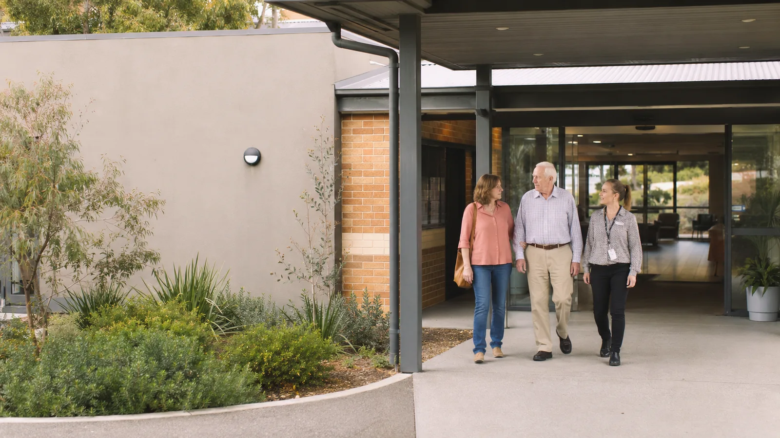 A family touring the entrance of an aged care facility with a staff member